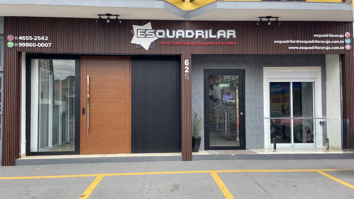 Fachada da loja da Esquadrilar em Arujá, com revestimento em ripas de madeira, letreiro ESQUADRILAR e porta pivotante de alumínio na vitrine